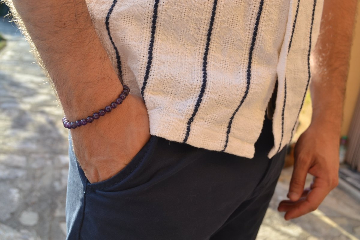 Bracelet Améthyste en pierre naturelle porté sur un poignet d'un homme au niveau de la hanche. perle de diamètre 5-6mm