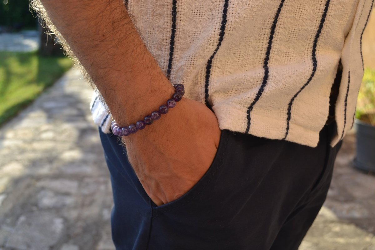 Bracelet Améthyste en pierre naturelle porté sur un poignet d'un homme au niveau de la hanche. perle de diamètre 7-8m