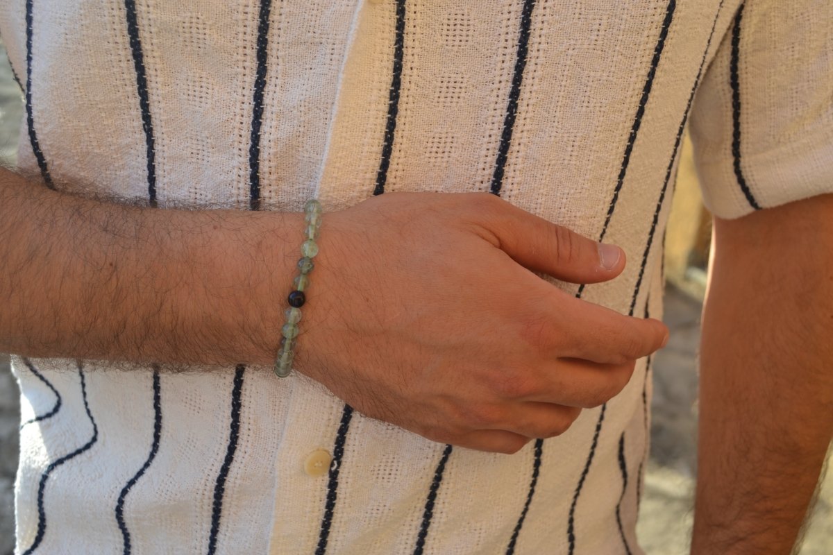 Bracelet Fluorite en pierre naturelle porté sur un poignet d'un homme au niveau du ventre. perle de diamètre 5-6mm