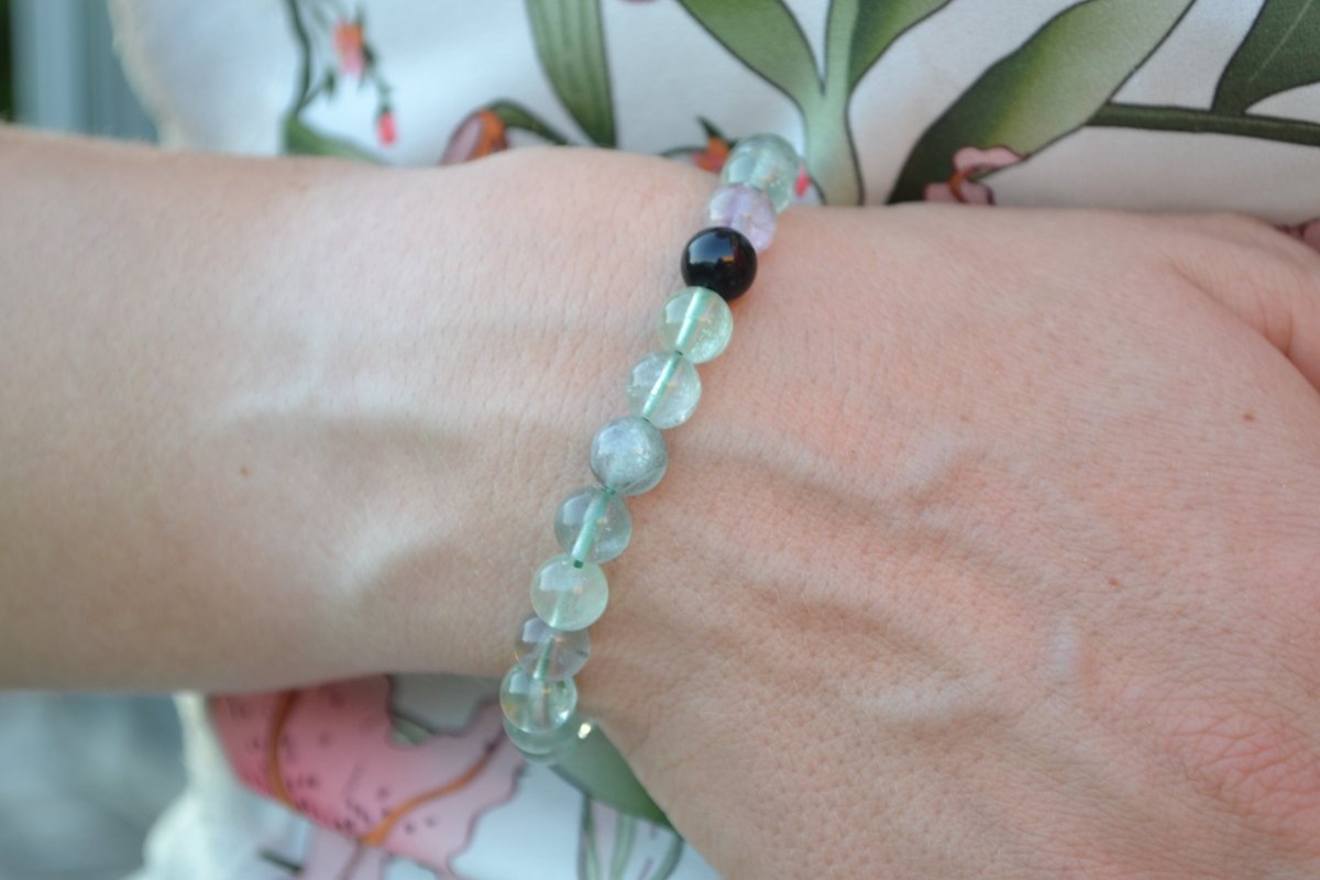 Bracelet Fluorite en pierre naturelle porté sur un poignet d'une femme au niveau du ventre. perle de diamètre 7-8mm