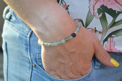 Bracelet Fluorite en pierre naturelle porté sur un poignet d'une femme au niveau de la hanche. perle de diamètre 5-6mm