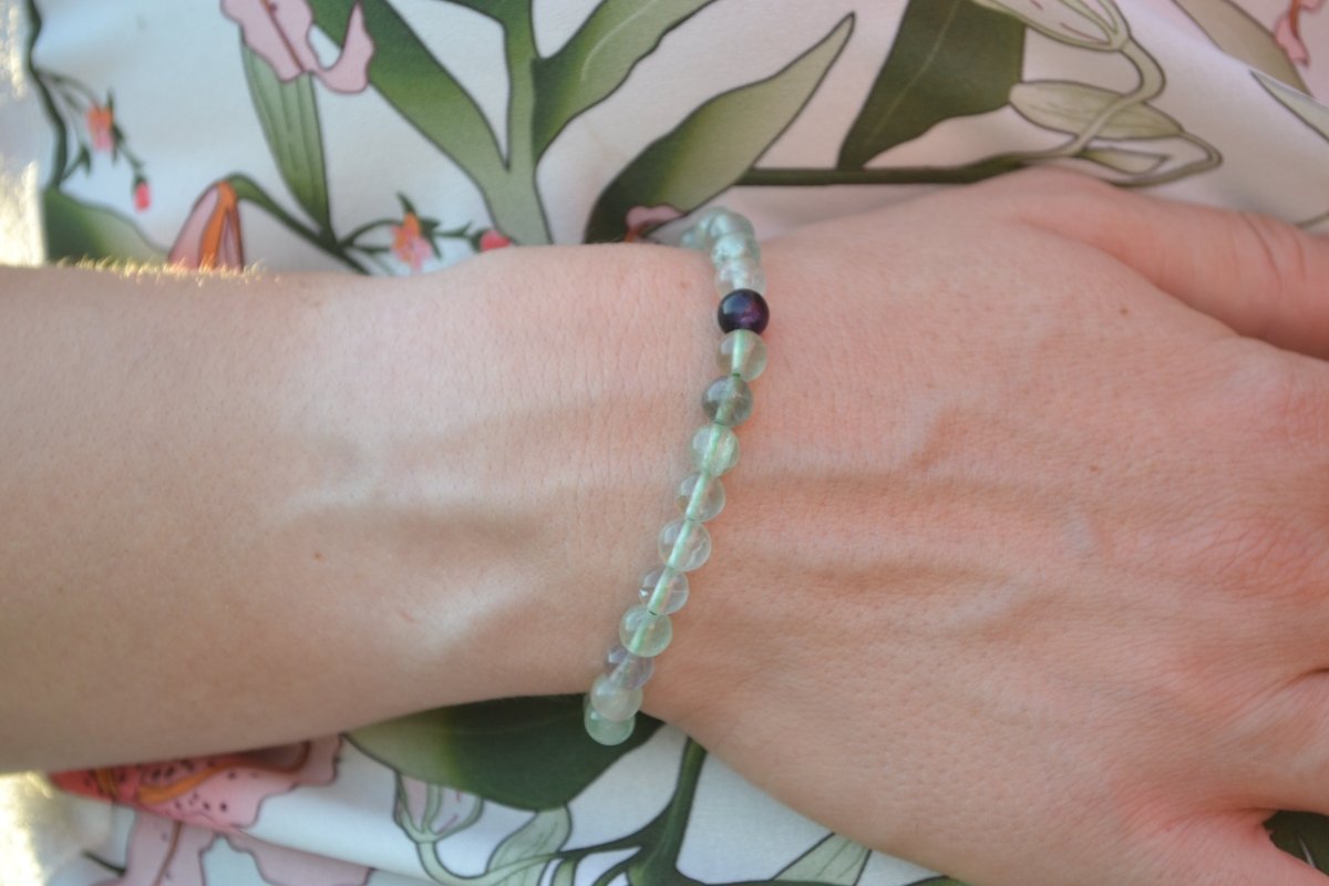 Bracelet Fluorite en pierre naturelle porté sur un poignet d'une femme au niveau du ventre. perle de diamètre 5-6mm