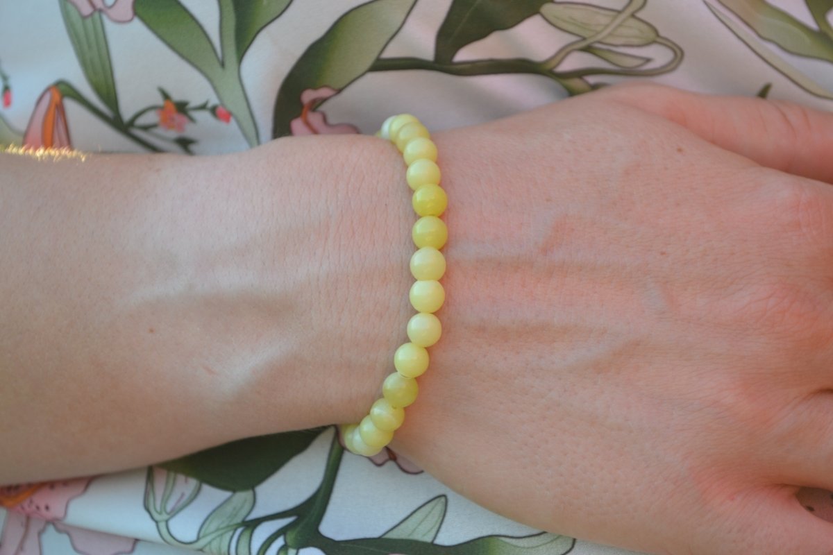 Bracelet Jade Citron en pierre naturelle porté sur un poignet d'une femme au niveau du ventre. perle de diamètre 5-6mm