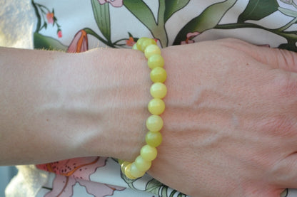 Bracelet Jade Citron en pierre naturelle porté sur un poignet d'une femme au niveau du ventre. perle de diamètre 7-8mm