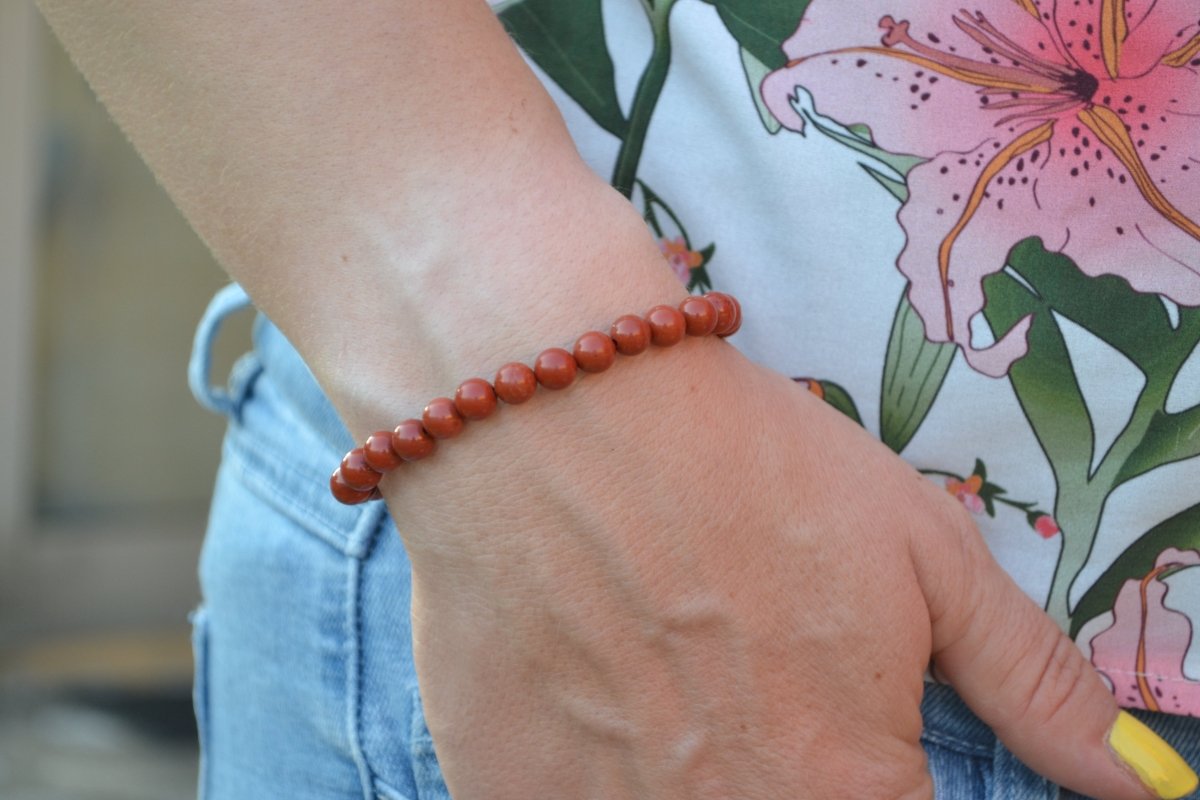 Bracelet Jaspe Rouge en pierre naturelle porté sur un poignet d'une femme au niveau de la hanche. perle de diamètre 5-6mm