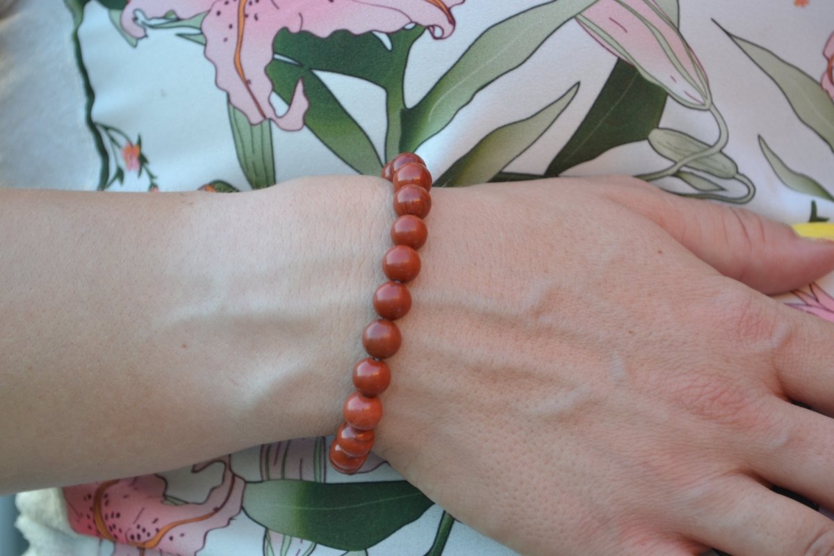 Bracelet Jaspe Rouge en pierre naturelle porté sur un poignet d'une femme au niveau du ventre. perle de diamètre 7-8mm