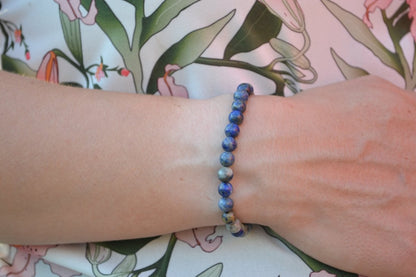 Bracelet Lapis Lazuli en pierre naturelle porté sur un poignet d'une femme au niveau du ventre. perle de diamètre -6mm