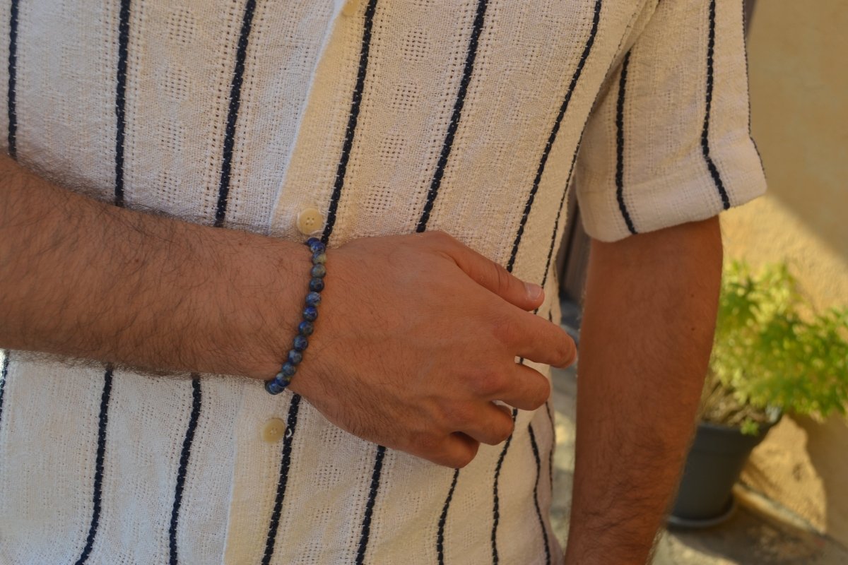 Bracelet Lapis Lazuli en pierre naturelle porté sur un poignet d'un homme au niveau du ventre. perle de diamètre 5-6mm