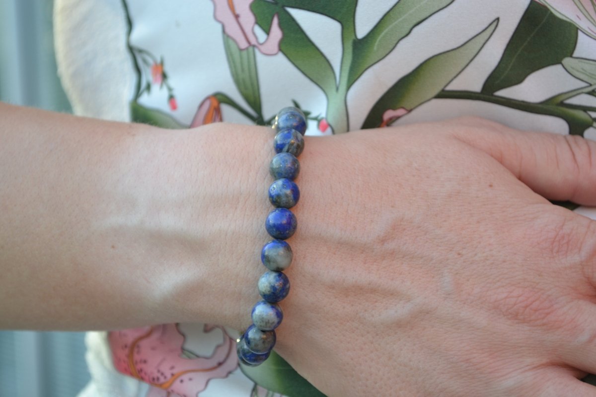 Bracelet Lapis Lazuli en pierre naturelle porté sur un poignet d'une femme au niveau du ventre. perle de diamètre 7-8mm