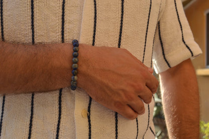 Bracelet Lapis Lazuli en pierre naturelle porté sur un poignet d'un homme au niveau du ventre. perle de diamètre 7-8mm
