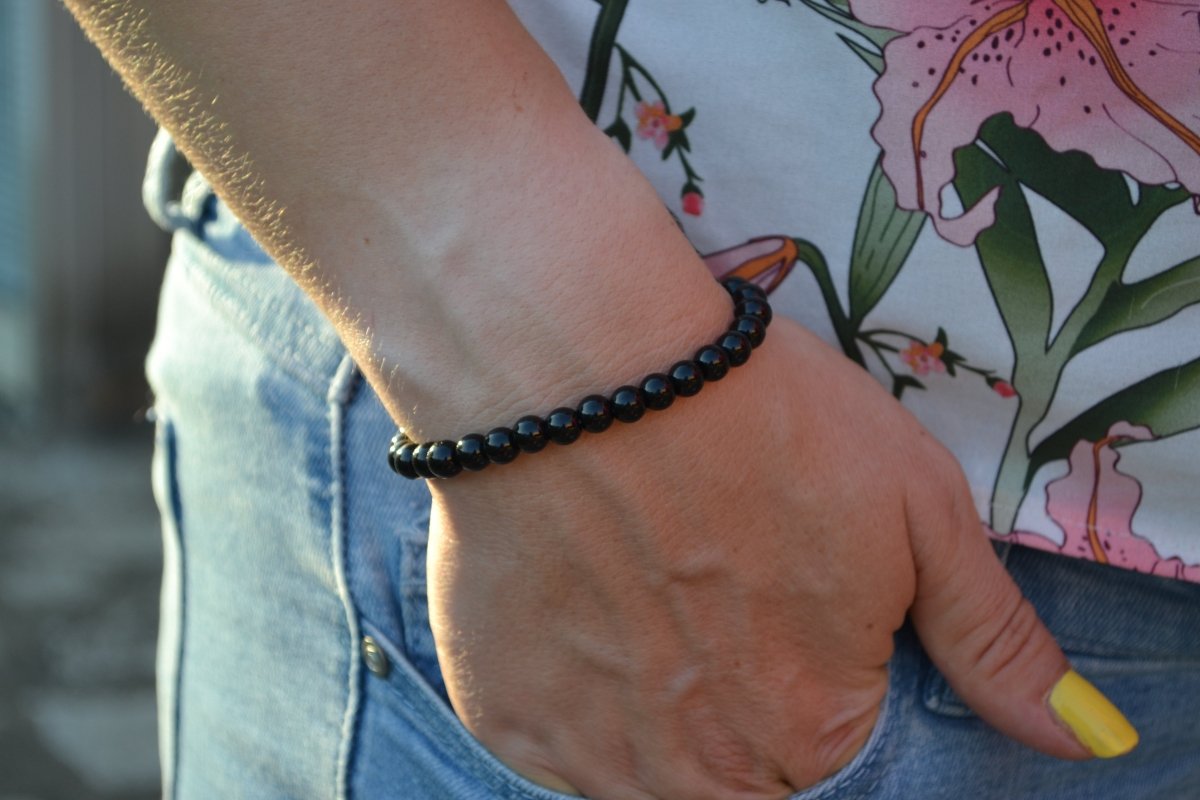 Bracelet Onyx en pierre naturelle porté sur un poignet d'une femme au niveau de la hanche. perle de diamètre 5-6mm