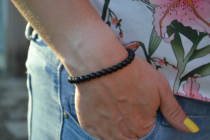 Bracelet Onyx en pierre naturelle porté sur un poignet d'une femme au niveau de la hanche. perle de diamètre 5-6mm