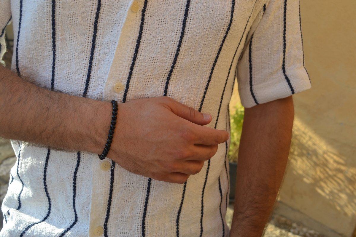 Bracelet Onyx en pierre naturelle porté sur un poignet d'un homme au niveau du ventre. perle de diamètre 5-6mm
