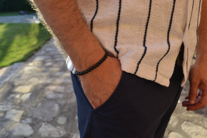 Bracelet Onyx en pierre naturelle porté sur un poignet d'un homme au niveau de la hanche. perle de diamètre 5-6mm