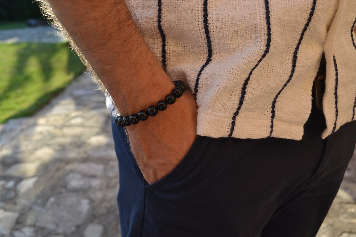 Bracelet Onyx en pierre naturelle porté sur un poignet d'un homme au niveau de la hanche. perle de diamètre 7-8mm