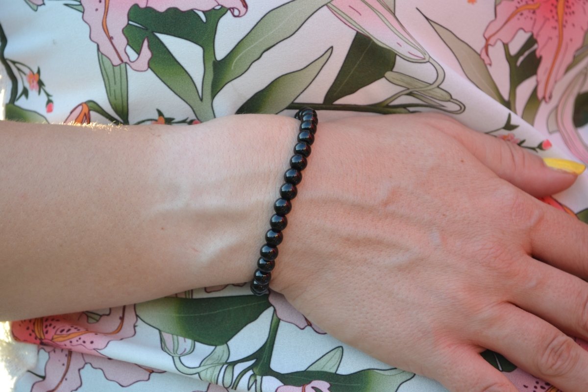 Bracelet Onyx en pierre naturelle porté sur un poignet d'une femme au niveau du ventre. perle de diamètre 5-6mm
