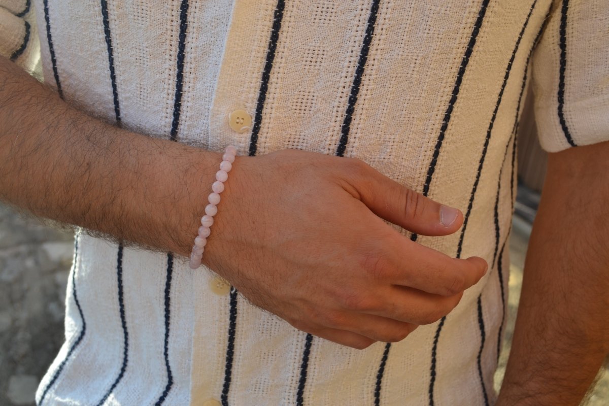 Bracelet Quartz Rose en pierre naturelle porté sur un poignet d'un homme au niveau du ventre. perle de diamètre 5-6mm