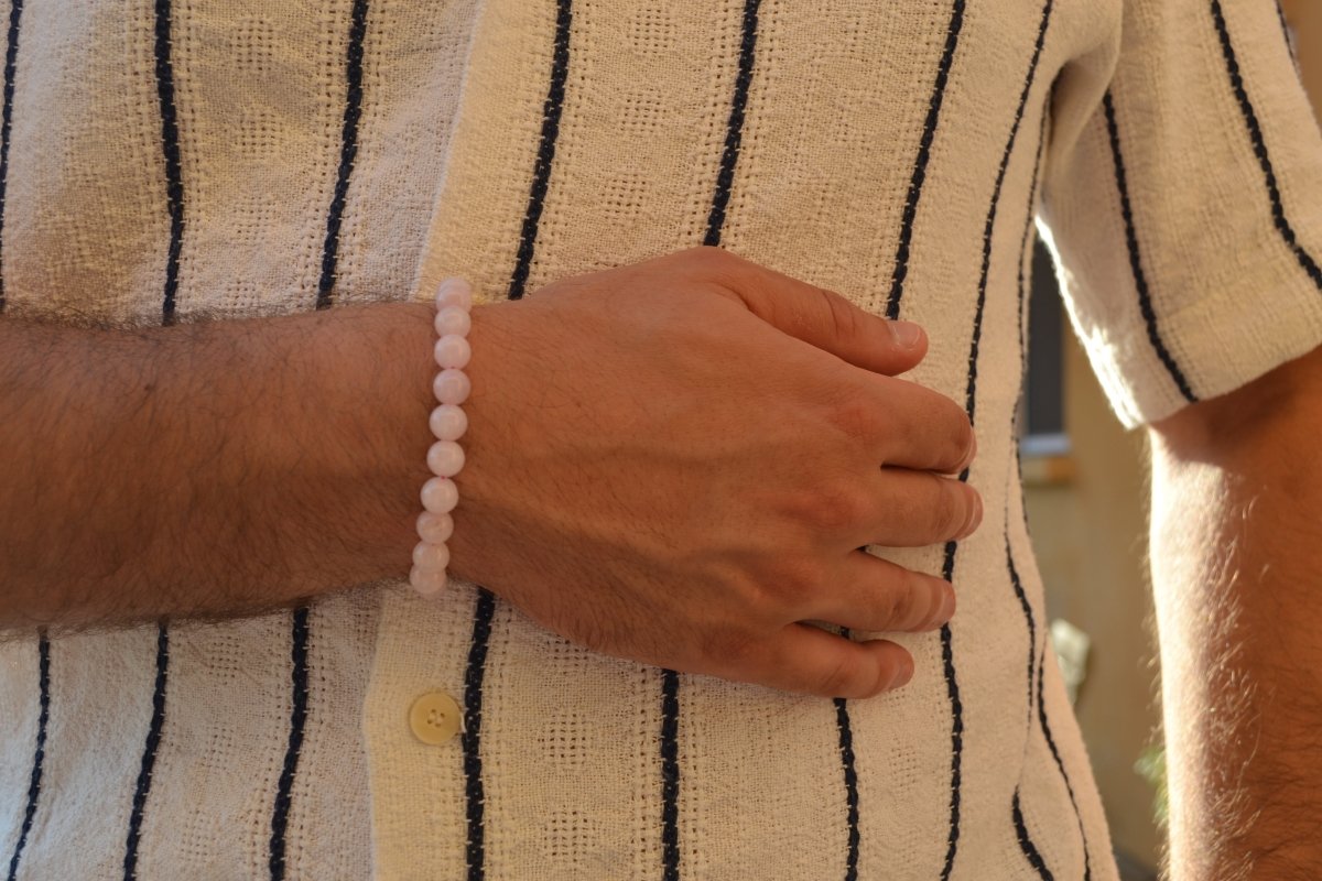 Bracelet Quartz Rose en pierre naturelle porté sur un poignet d'un homme au niveau du ventre. perle de diamètre 7-8mm
