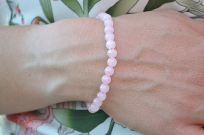 Bracelet Quartz Rose en pierre naturelle porté sur un poignet d'une femme au niveau du ventre. perle de diamètre 5-6mm