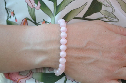 Bracelet Quartz Rose en pierre naturelle porté sur un poignet d'une femme au niveau du ventre. perle de diamètre 7-8mm