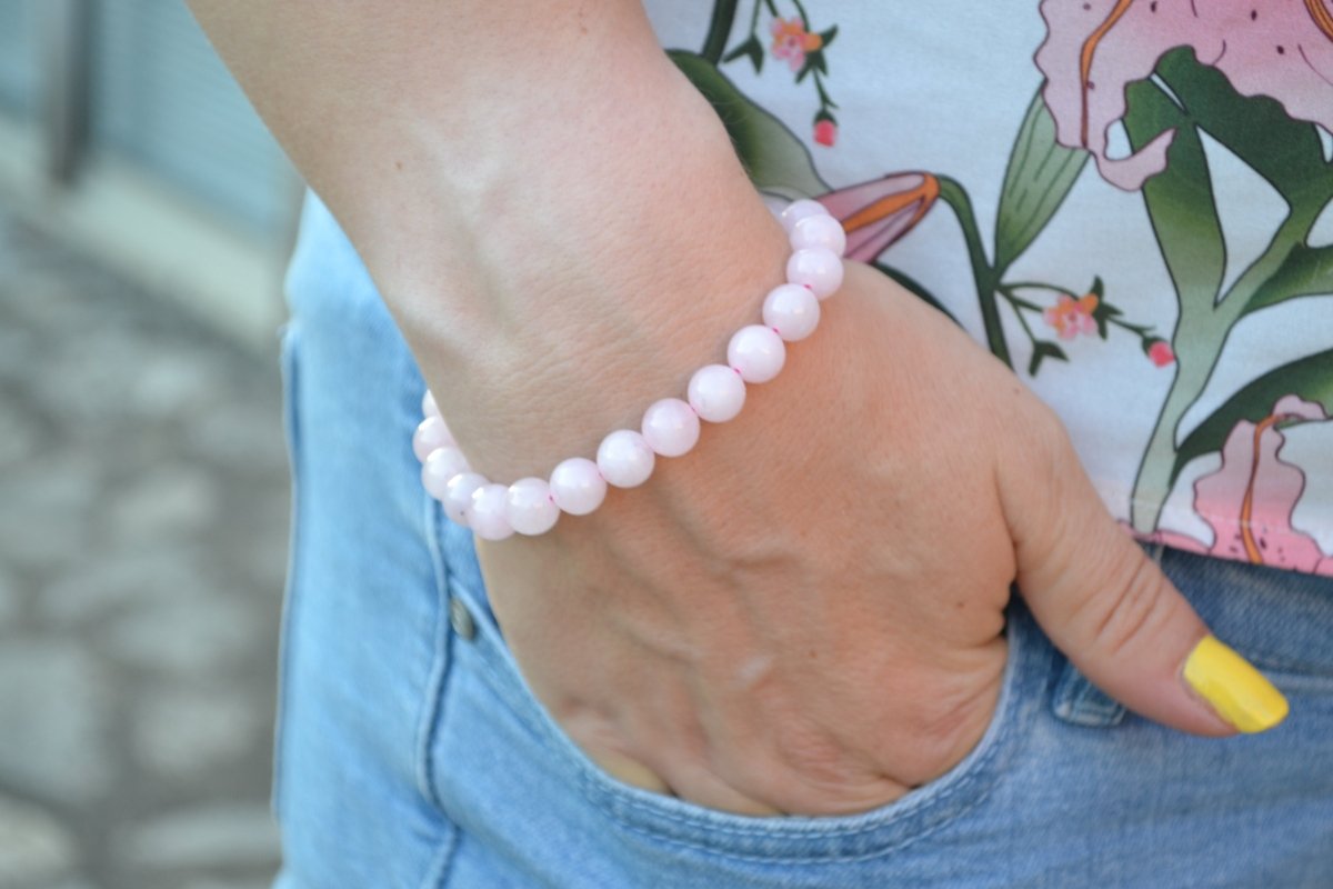 Bracelet Quartz Rose en pierre naturelle porté sur un poignet d'une femme au niveau de la hanche. perle de diamètre 7-8mm