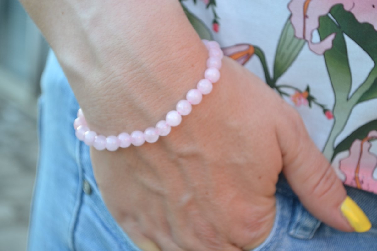 Bracelet Quartz Rose en pierre naturelle porté sur un poignet d'une femme au niveau de la hanche. perle de diamètre 5-6mm