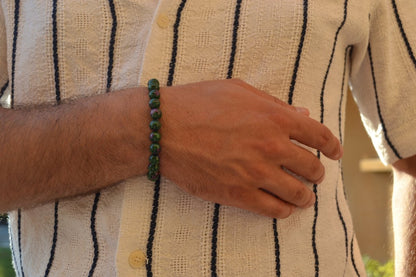 Bracelet Rubis Zoïsite en pierre naturelle porté sur un poignet d'un homme au niveau du ventre. perle de diamètre 5-6mm