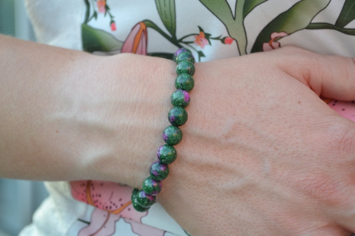 Bracelet Rubis Zoïsite en pierre naturelle porté sur un poignet d'une femme au niveau du ventre. perle de diamètre 7-8mm