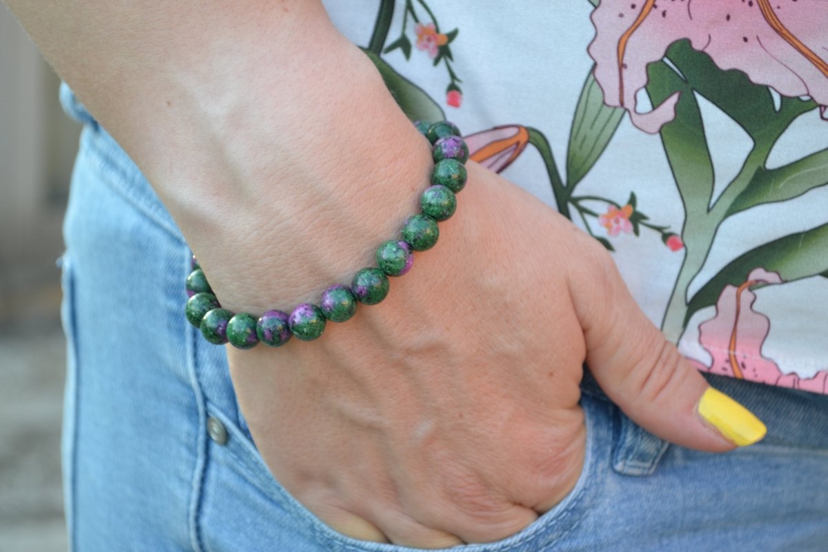 Bracelet Rubis Zoïsite en pierre naturelle porté sur un poignet d'une femme au niveau de la hanche. perle de diamètre 7-8mm