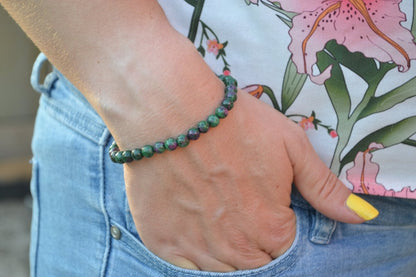 Bracelet Rubis Zoïsite en pierre naturelle porté sur un poignet d'une femme au niveau de la hanche. perle de diamètre 5-6mm