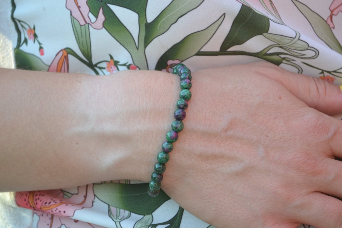 Bracelet Rubis Zoïsite en pierre naturelle porté sur un poignet d'une femme au niveau du ventre. perle de diamètre 5-6mm