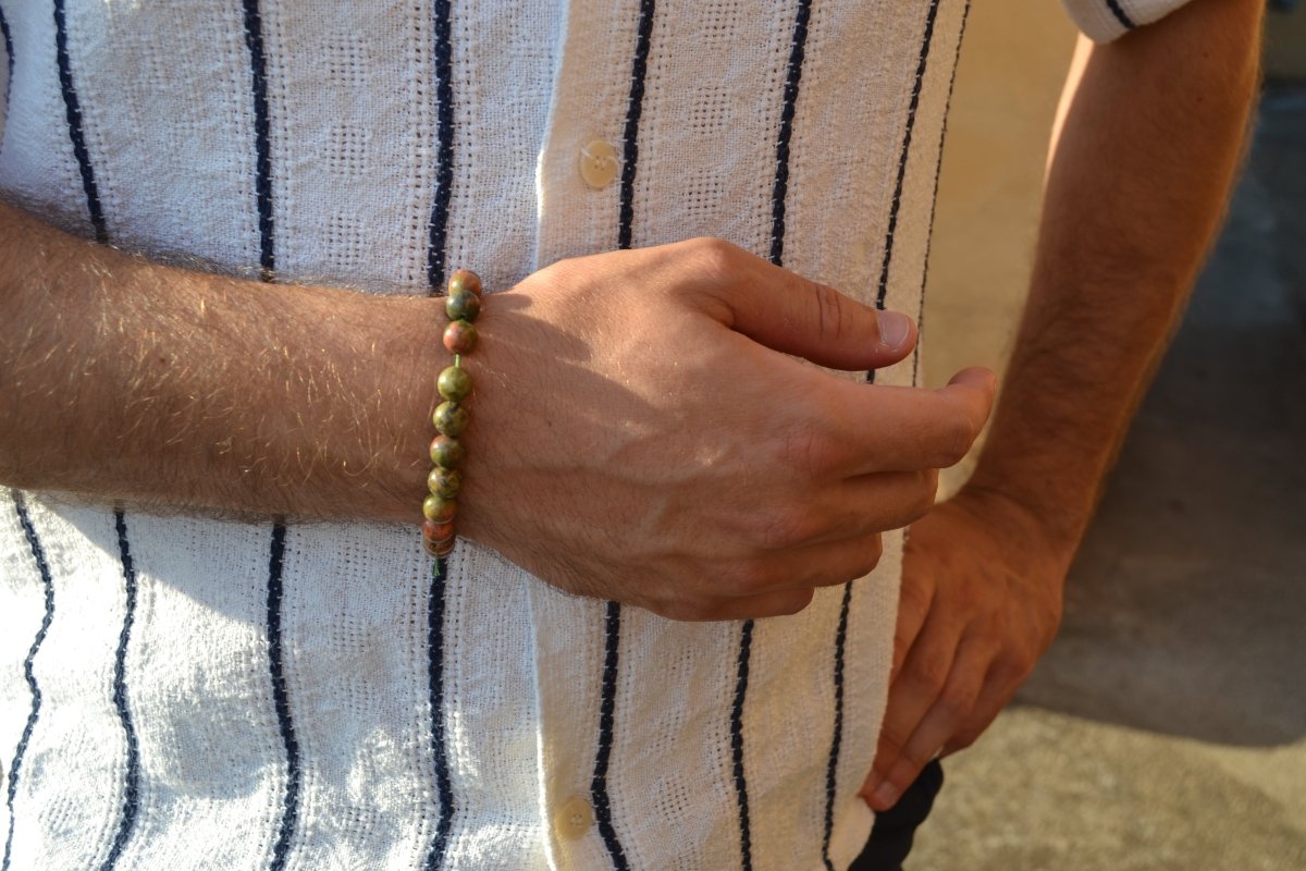 Bracelet Unakite en pierre naturelle porté sur un poignet d'un homme au niveau du ventre. perle de diamètre 7-8mm