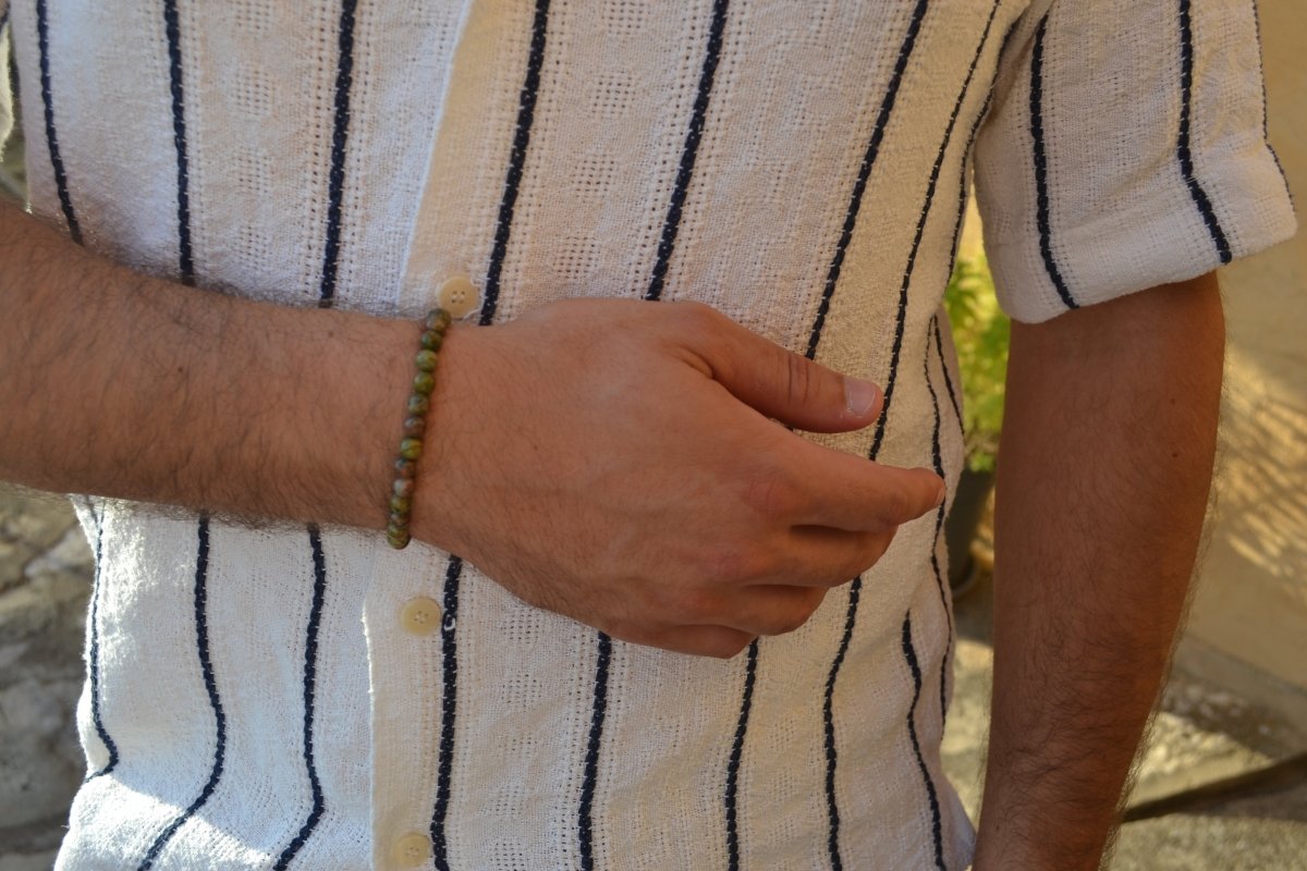 Bracelet Unakite en pierre naturelle porté sur un poignet d'un homme au niveau du ventre. perle de diamètre 5-6mm