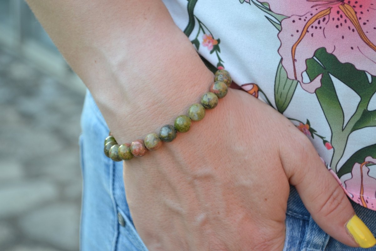 Bracelet Unakite en pierre naturelle porté sur un poignet d'une femme au niveau de la hanche. perle de diamètre 7-8mm