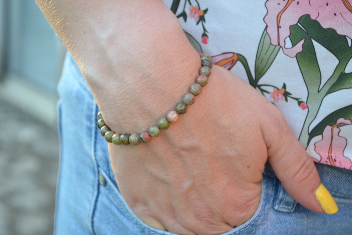 Bracelet Unakite en pierre naturelle porté sur un poignet d'une femme au niveau de la hanche. perle de diamètre 5-6mm