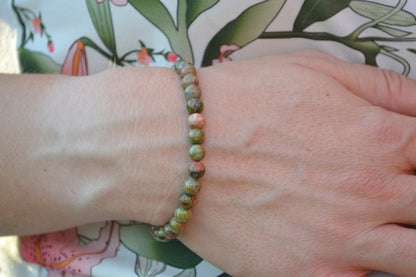 Bracelet Unakite en pierre naturelle porté sur un poignet d'une femme au niveau du ventre. perle de diamètre 5-6mm