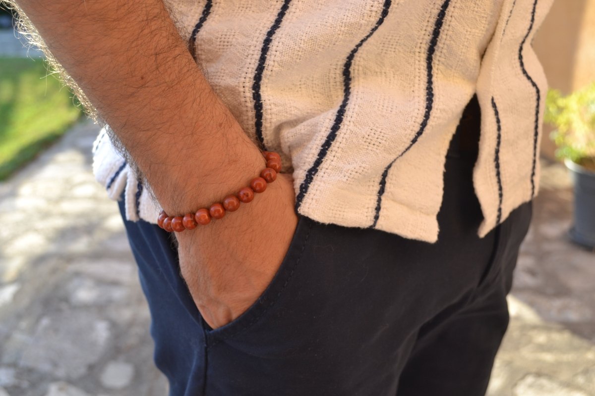 Bracelet Jaspe Rouge en pierre naturelle porté sur un poignet d'un homme au niveau de la hanche. perle de diamètre 7-8mm