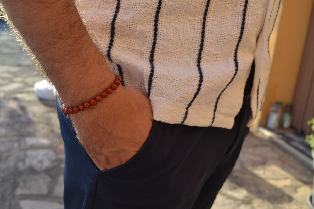 Bracelet Jaspe Rouge en pierre naturelle porté sur un poignet d'un homme au niveau de la hanche. perle de diamètre 5-6mm